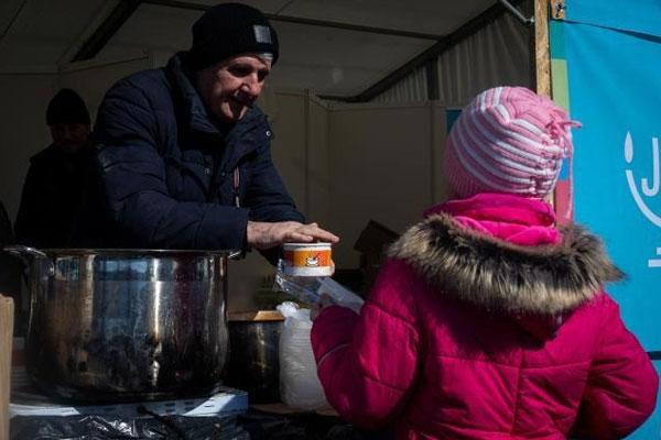 A volunteer serving soup to an Ukrainian child at the border between Ukraine and Romania