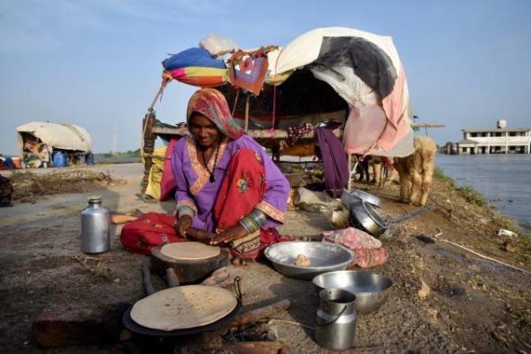A flood-affected woman is cooking bread outside her tent