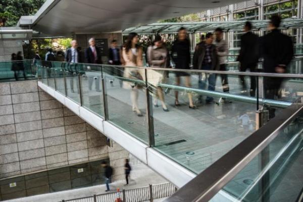 Office workers walking on a pedestrian bridge in the central business district of Hong Kong