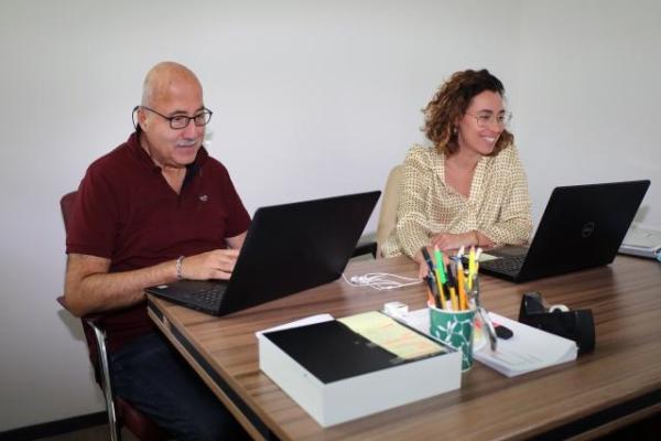 A man and a young woman working on their laptops in an office