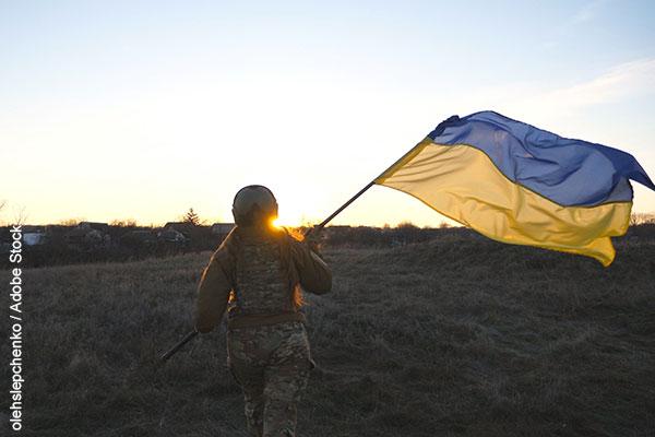 Female ukrainian army soldier runs and waves flag of Ukraine at sunset