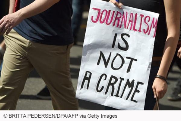 People holding a poster that says: Journalism is not a crime