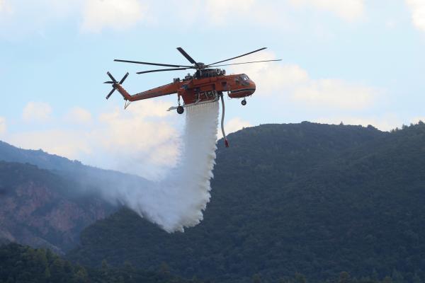 A helicopter of the Greek Civil Protection dropping water in the forest to extinguish the fire