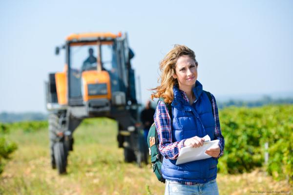 Woman standing in vineyard with tractor in background