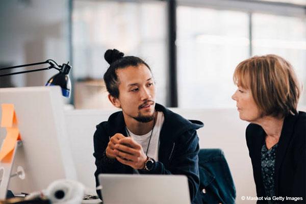 Man and woman sat at desk in front of computer