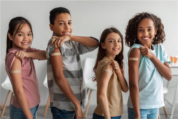 Four smiling children showing their arms after vaccination