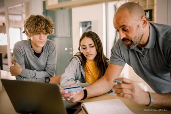 A man with two kids in front of a laptop holding a credit card