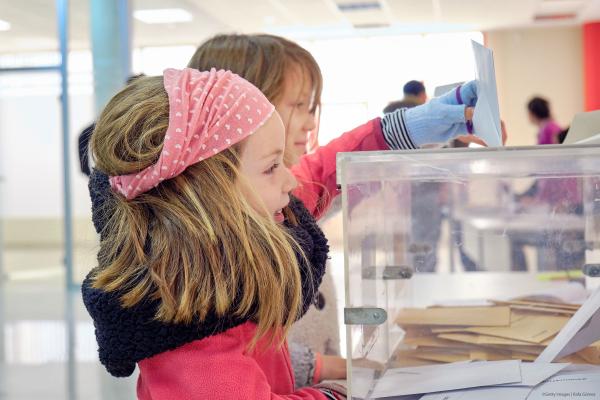 Young girl posts vote in transparent voting box