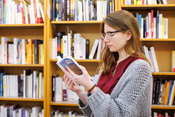 Young girl reading a book in a library