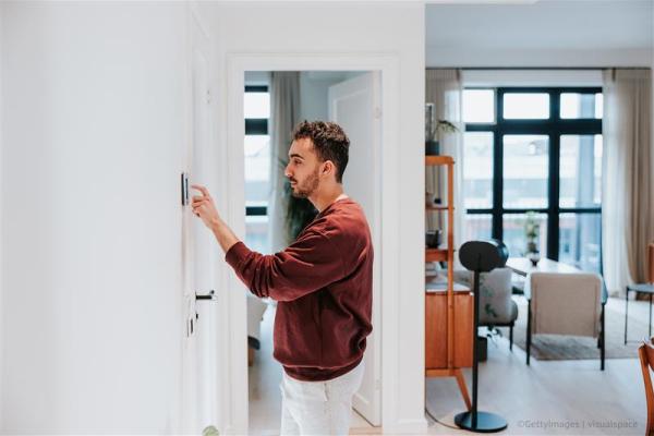 A man adjusting the thermostat in his apartment