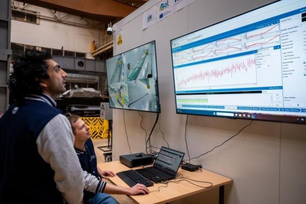 A teacher and student monitoring data on a screen