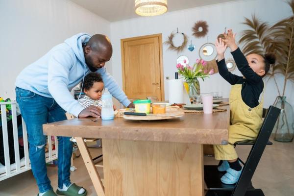 Man with his two children at the kitchen table in his house