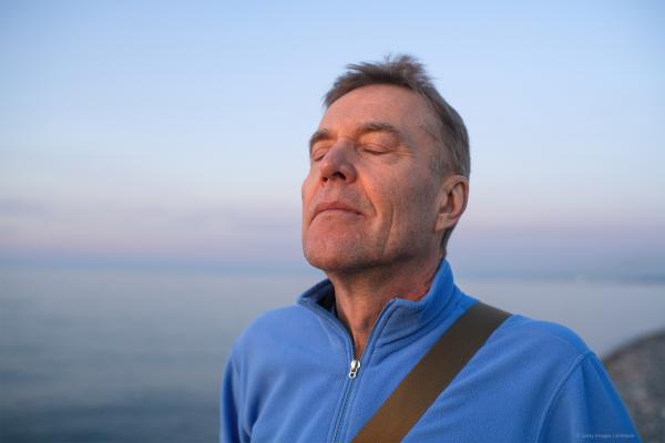 Man with his eyes closed faces towards the sun - mental health